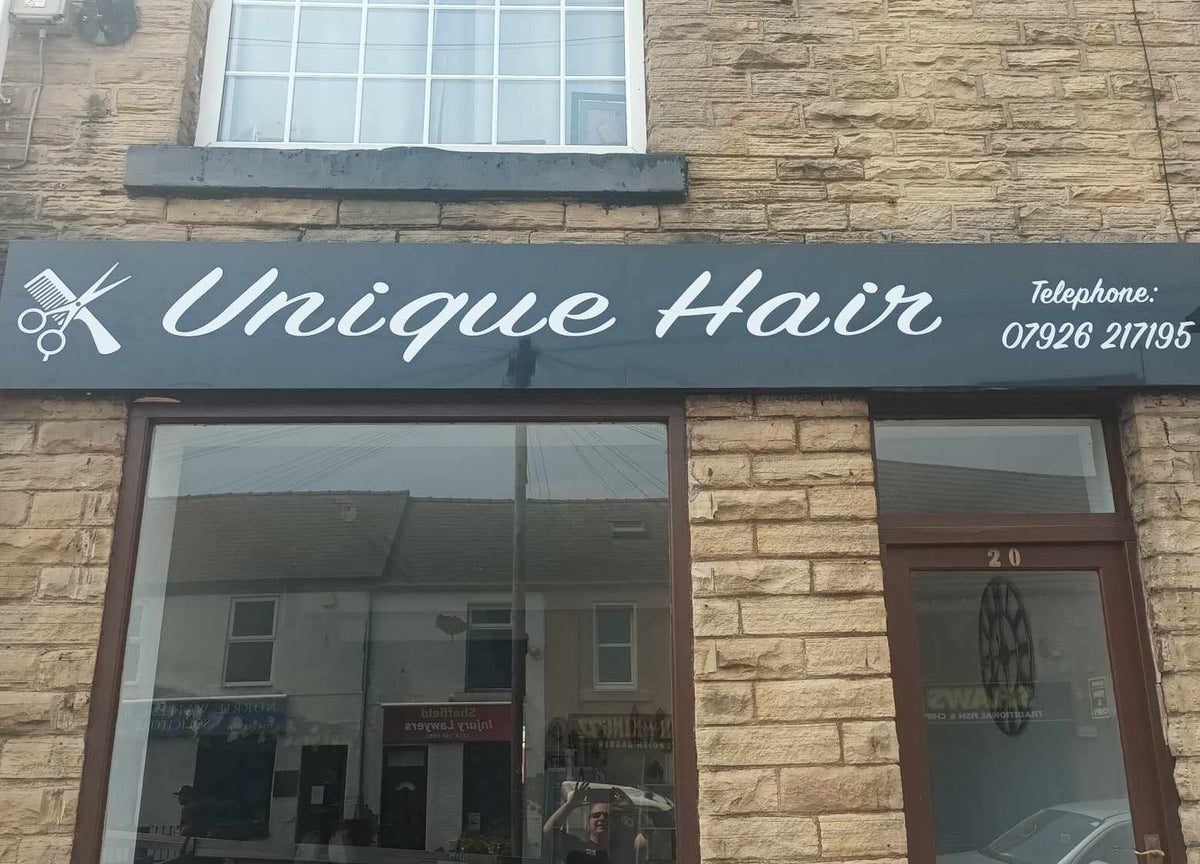 Storefront with 'Unique Hair' sign on a brick building by trailblazersbrandingco
